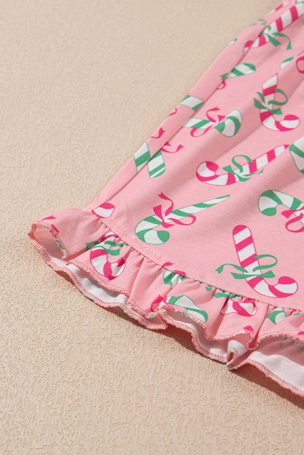 Roze kerstpyjamaset met knoop en zakmotief in zuurstokprint