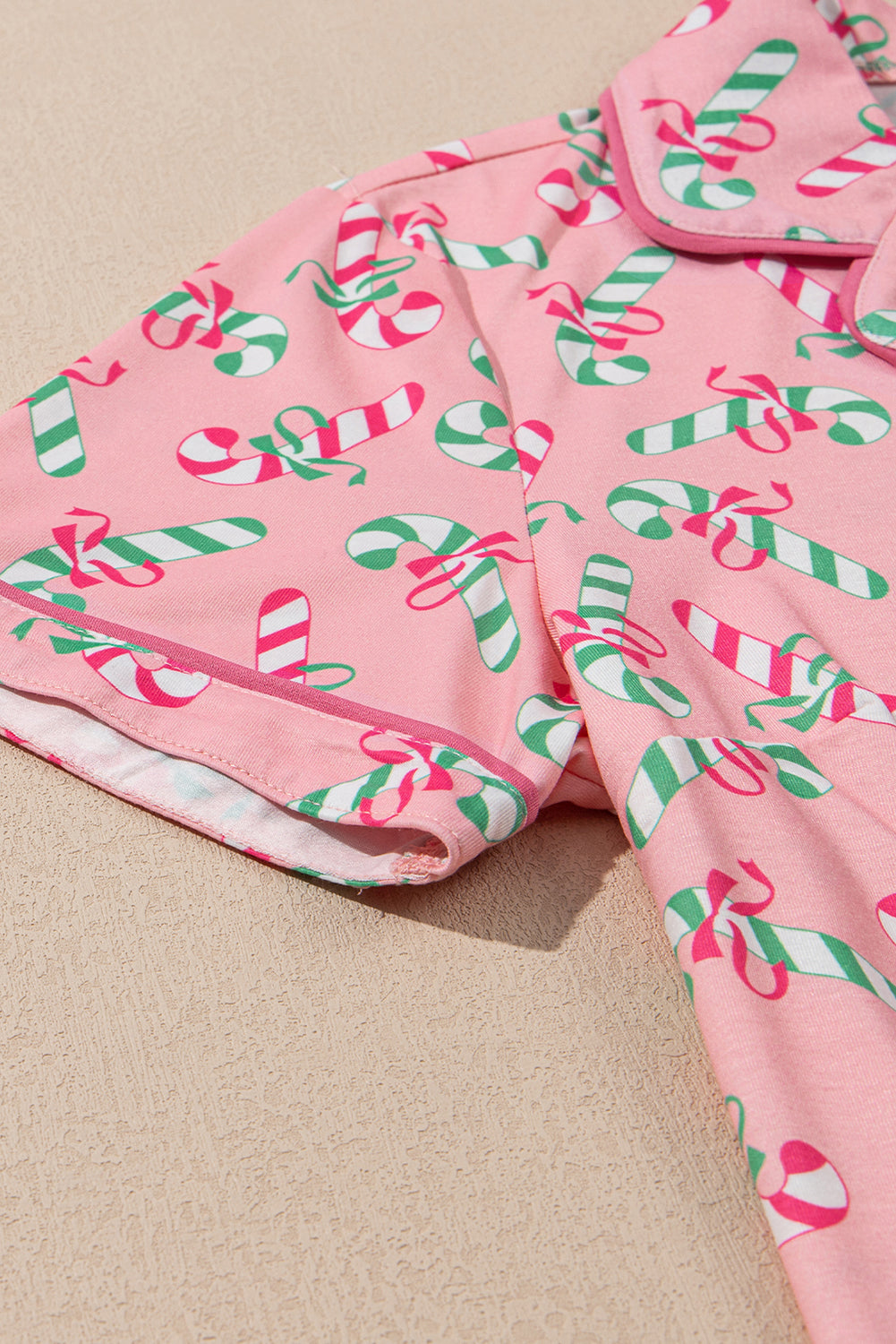 Roze kerstpyjamaset met knoop en zakmotief in zuurstokprint